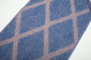 Détail de la texture de l'écharpe en maille à carreaux bleu marine et rose