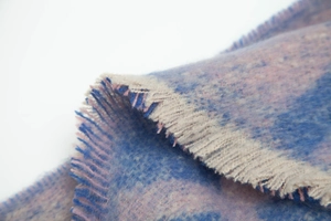 Gros plan sur la texture de l'écharpe à carreaux bleu et rose avec franges