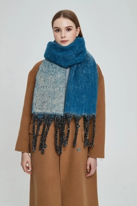 Close-up of thick gradient blue shawl scarf with chunky knit fringe details on model