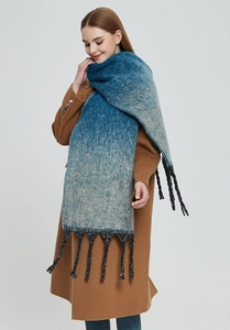 Detail of blue gradient winter scarf featuring thick twisted tassels and knit texture
