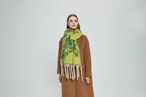 Detail of winter knit scarf with yellow green floral jacquard and thick cream tassels