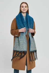 Detail of blue gradient thick scarf with chunky black tassels on brown wool coat