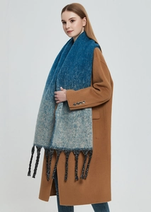 Close-up detail of gradient knit scarf with thick tassels and soft wool-like texture