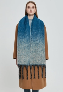 Detail of gradient blue knit scarf featuring thick textured tassels on an autumn coat