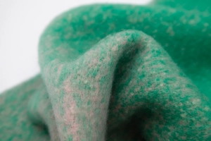Macro shot of thick green gradient knit scarf featuring fluffy loop yarn and fringed texture
