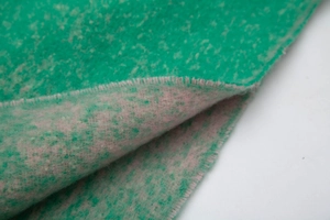 Detailed macro view of dual-sided knit scarf showing thick green and purple mixed yarn texture