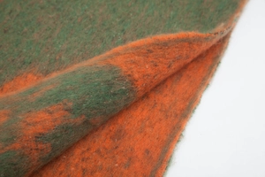 Detailed texture of thick mohair-style jacquard scarf with green and orange floral pattern