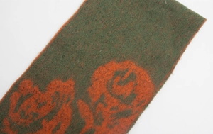 Close-up of thick brushed knit scarf with large orange rose patterns on dark green fabric