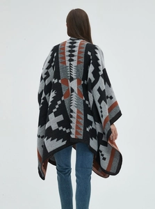 Dettaglio del poncho in maglia geometrica con motivi etnici e trama spessa