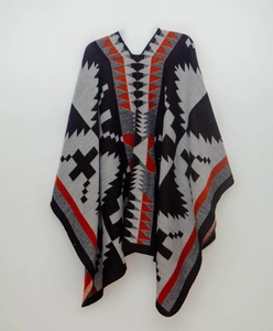 Dettaglio del poncho in maglia geometrica con motivi etnici in nero e arancione