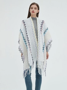 Detail of white knit shawl featuring colorful wavy patterns and dense fringe trim