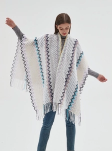 Close-up of white knitted shawl with zigzag patterns and fringe tassels for women