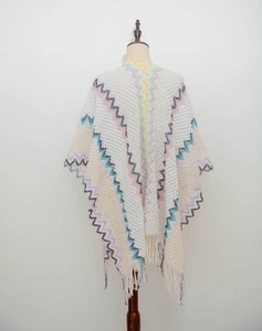 Detail of bohemian white knit shawl with colorful wave patterns and long tassel fringe