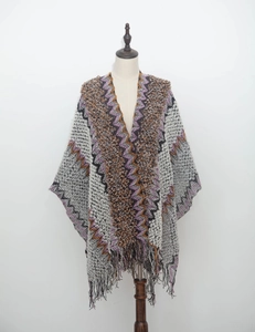 Detail of bohemian knitted poncho with colorful geometric patterns and long fringe tassels
