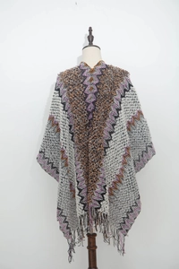 Detail of multi-color wavy knit poncho featuring geometric patterns and fringe hem