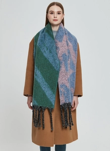 Detailed view of thick knit scarf with mixed color blocks and long fringe trim