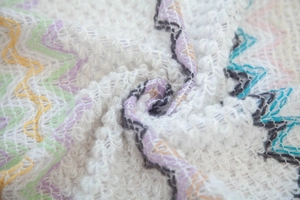 Macro shot of colorful zigzag knit fabric with soft texture and refined tassel details