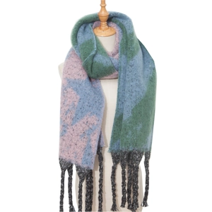 Detail of chunky knit scarf with green and blue color blocking and thick black fringe