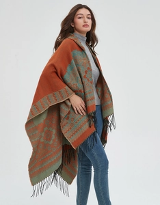 Détail d'un poncho en tricot ethnique avec motifs orange et vert et franges noires
