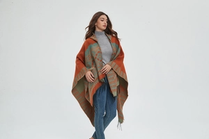 Détail d'un poncho en tricot bohème avec motifs floraux vintage et finitions à franges