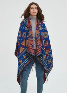Close-up of bohemian knit poncho with royal blue geometric patterns and black tassels