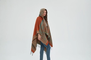 Détail du poncho à capuche montrant des motifs jacquard colorés et des franges noires