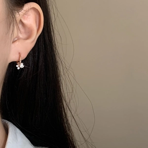 Elegant gold hoop earrings with sparkling flower-shaped zirconia pendants worn by a model