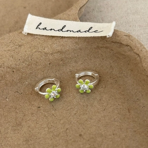 Vue détaillée des boucles d'oreilles fleur en émail vert avec un zircon étincelant