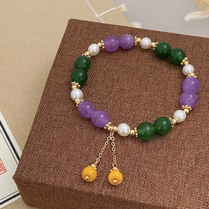 Colorful natural stone and pearl beaded bracelet with gold tassel pendant on jewelry box