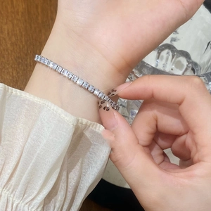 Sparkling silver tennis bracelet with square-cut zircons worn on a female wrist