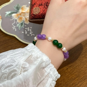 Handcrafted pearl and gemstone beaded bracelet with gold accents on model's wrist