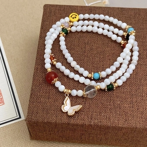 Dettaglio del bracciale a strati con ciondolo a farfalla in conchiglia e perline colorate