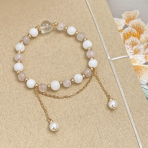 Macro shot of natural stone bead bracelet with gold chain tassels and pearl charms