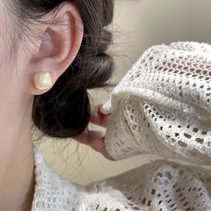 Square cream pearl stud earrings with vintage minimalist design on a female model