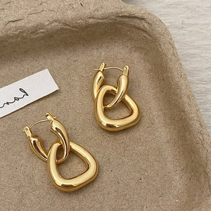 Detailed view of interconnected gold geometric earrings on a textured tray