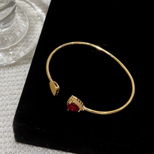18K gold plated open bangle featuring a large red heart zircon and a solid gold heart