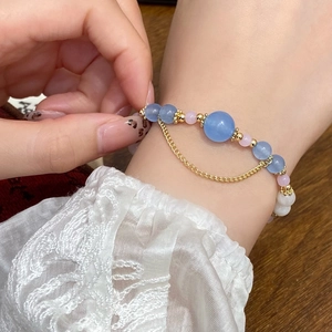 Handmade beaded bracelet with blue and pink stones, golden fringe, and lace cuff details