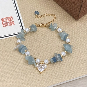 Detailed macro view of beaded bracelet with blue crystals, pearls and heart zircon pendant