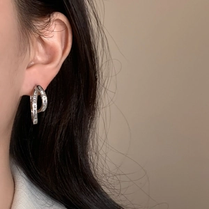 Detail shot of irregular silver hoop earrings with rectangular zircon channel setting