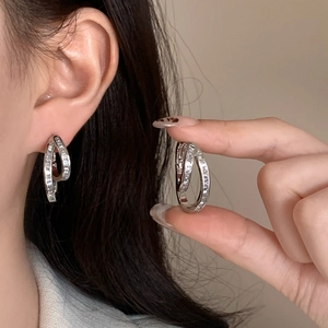 Detail of silver double hoop earrings with cubic zirconia shown on model and held in hand