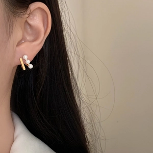 French style gold bar earring with three elegant pearls worn on a model's ear