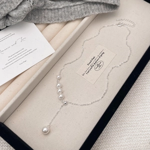 Detail of adjustable French style Y-necklace with elegant tassels and white pearls
