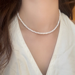 Detail of elegant handmade pearl choker necklace on model with silk V-neck top