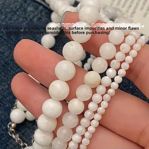 Macro detail of natural white seashell beads in four sizes on blue denim fabric