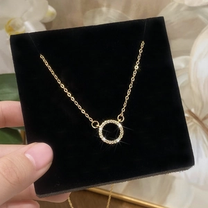 Gold plated circular pendant necklace with micro-paved cubic zirconia on black velvet