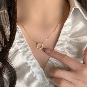 Gold plated circular pendant necklace with micro-paved zircons worn on a model