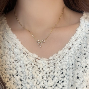 Gold bow pendant necklace with micro-set zircons and pearls on a female model
