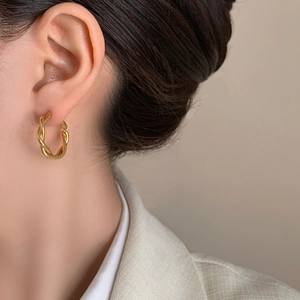 Minimalist twisted golden hoop earrings featuring a spiral weave design for a modern look