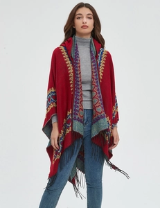 Détail du châle à capuche rouge avec motifs ethniques et finitions à franges noires
