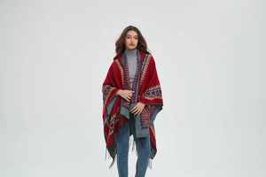 Détail d'un poncho rouge à capuche avec motifs ethniques de cœur et franges noires